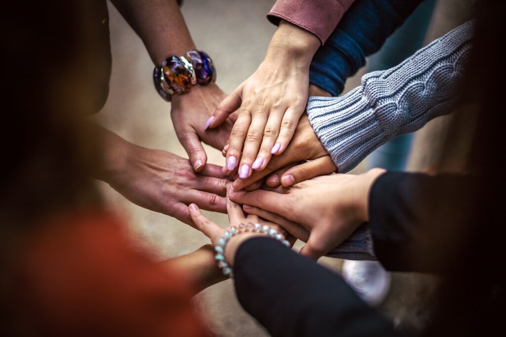 9 multicultural patients hold hands outside a FQHC 340B clinic