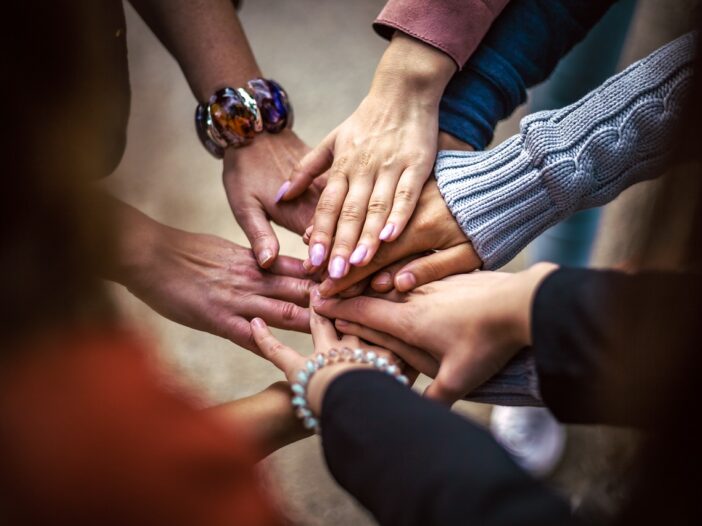 9 multicultural patients hold hands outside a FQHC 340B clinic