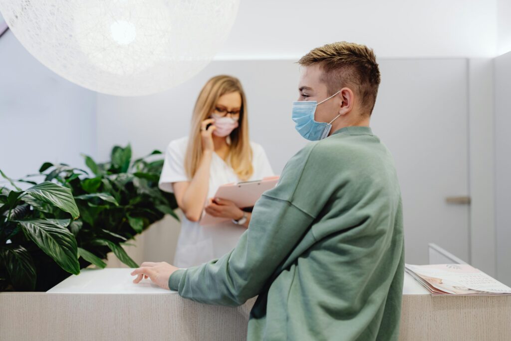 A man stands at the front desk of a FQHC, waiting to check in for an IV infusion therapy appointment