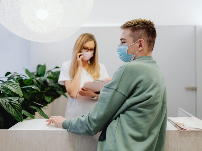 A man stands at the front desk of a FQHC, waiting to check in for an IV infusion therapy appointment