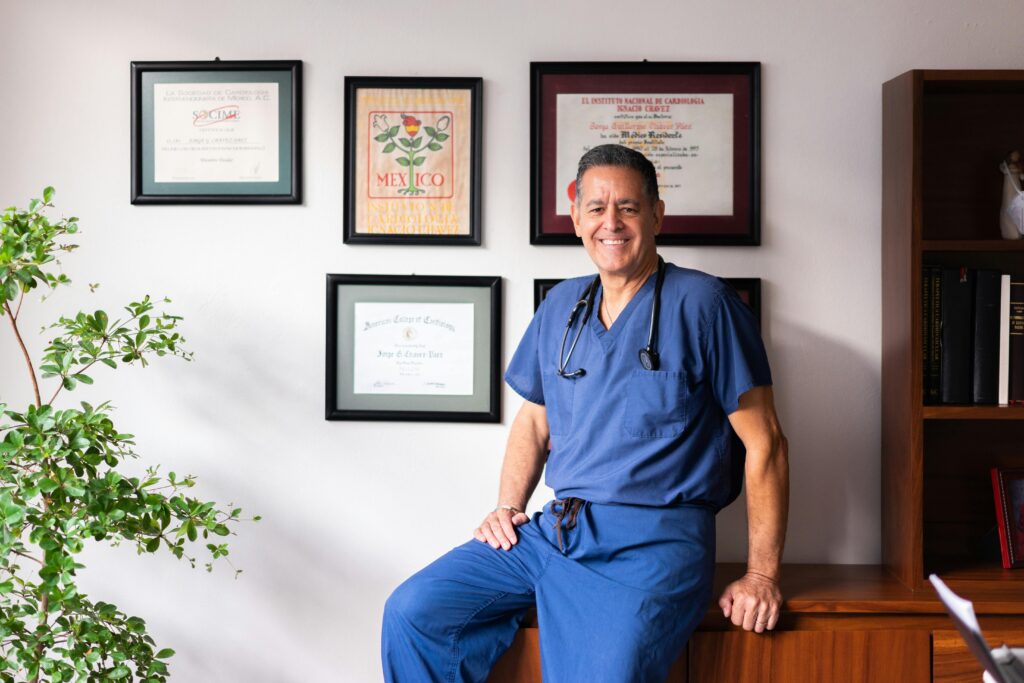 Male doctor in blue scrubs displays diplomas at FQHC clinic